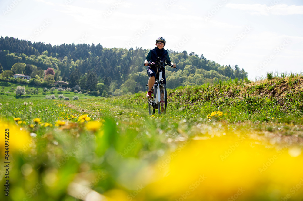 Querfeldein mit dem E-Bike durch den Frhling, Frau geniet Fahrrad fahren  in der Natur. | Adobe Stock