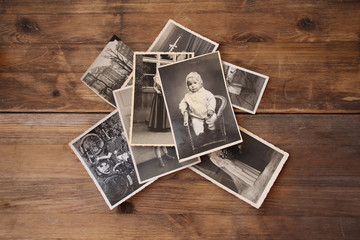 old vintage monochrome photographs in sepia color are scattered on a wooden table, the concept of genealogy, the memory of ancestors, family ties, memories of childhood