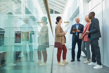 Sticker - Group of young business people talking to each other while standing at corridor and waiting for the beginning of seminar