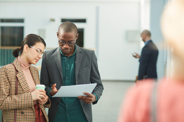 Sticker - Multiethnic business couple examining the contract together while standing at office corridor