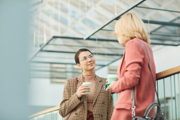 Sticker - Two young businesswomen drinking coffee and talking to each other during coffee break