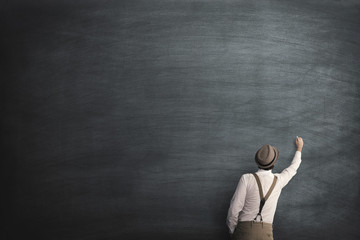 student writing on an empty blackboard with chalk
