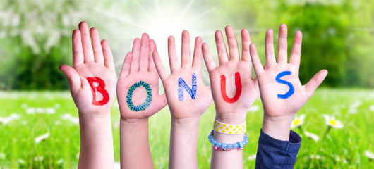 Wall Mural - Children Hands Building Colorful Word Bonus. Sunny Green Grass Meadow As Background