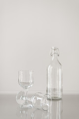 Two empty wine glasses and bottle for water on transparent table