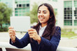 © Mangostar - Content young woman using tablet pc. Cheerful young businesswoman having video chat via digital tablet in urban city. Communication concept