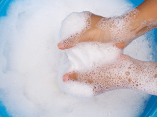 top view of hands are washing clothes with detergent with blue basin.