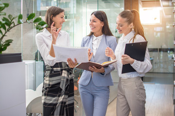 Wall Mural - Beautiful businesswomen discussing over paperwork in office lobby.