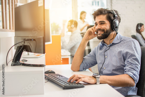 Fotomural Smiling friendly handsome young male call centre operator.