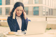 © Mangostar - Tired businesswoman using laptop in outdoor cafe. Overworked middle aged businesswoman working with laptop computer while sitting at table with coffee outdoors. Technology concept