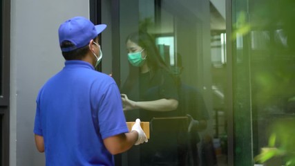 Wall Mural - Corona Virus Concept. Asian blue delivery man wearing protection mask and medical rubber gloves send a package to customer on before deliver cargo. 4k resolution and slow motion shot.