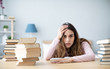 © BestForYou - Sad young woman lying on table with books at home.