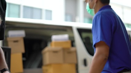 Wall Mural - Close up asian blue delivery man wearing medical rubber gloves send a package to customer on before deliver cargo. 4k resolution and slow motion shot.