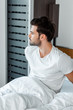 © LIGHTFIELD STUDIOS - Handsome man looking away while sitting on bed