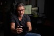 © nyul - Man using smart phone at home sitting in armchair in cosy living room.