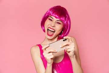 Canvas Print - Image of happy girl wearing wig playing video games on cellphone