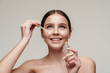 © Drobot Dean - Image of cheerful cute shirtless woman applying face serum and smiling