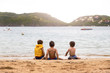 © AlexPhotoStock - Three little brazilian children playing on the beach, next to the water, in ferradura beach in buzios brazil. One of these with a yellow life jacket.