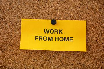 Work From Home written on a yellow piece of paper that is on a bulletin board