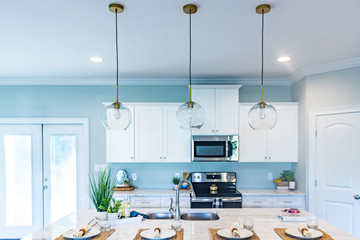 Open floor plan kitchen in a new construction empty house that has just been completed with white cabinets, pendant lighting, a bar area and hardwood floors