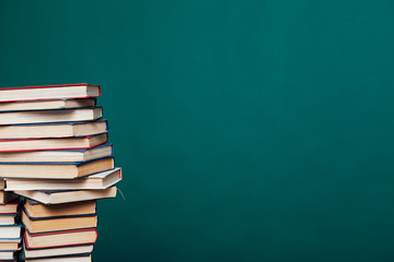 lots of stacks of educational books to teach in the school library on a green background