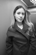 © hydraviridis - Portrait of a beautiful young woman with long hair and a black coat high-necked in a lift. Black and white.
