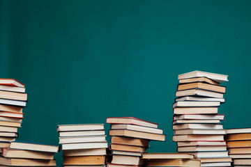 lots of stacks of educational books to teach in the school library on a green background