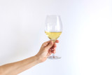 Fototapeta Storczyk - Woman hand holds gives a glass of champagne white wine on a white background. Place for text.
