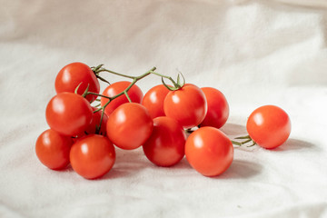 A branch with small tomatoes on a beige background.