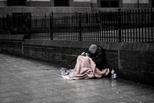 Beggar Sitting On Street Against Wall