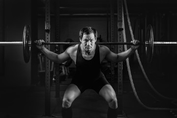 Wall Mural - asian athletic strong man having workout and bodybuilding with barbells weightlifting backsquat style in gym and fitness center in dark tone black and white