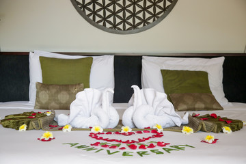 Luxury hotel bedroom interior with honeymoon decoration, Towel swans and rose flowers on the bed	
