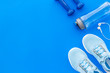 © 9dreamstudio - Fitness accessories. Dumbbells and sneakers on blue table top view copy space