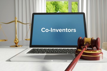 Co-Inventors – Law, Judgment, Web. Laptop in the office with term on the screen. Hammer, Libra, Lawyer.