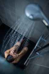 Wall Mural - Pretty, young woman taking a long hot shower washing her hair in a modern design bathroom (color toned image)