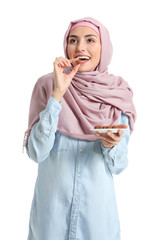 Sticker - Beautiful Muslim woman eating tasty chocolate candies on white background