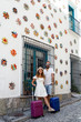 © marina - Happy couple on vacation with suitcases in an Andalusian town with typical and colorful architecture