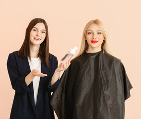 Canvas Print - Young hairdresser working with client against color background