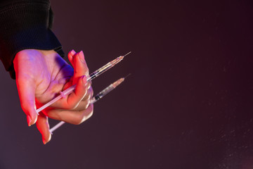 copy space a young female hand holds a syringe against the background of a mirrored table, the subject of medium shot. The concept of quarantine coronavirus versus addiction