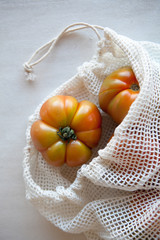 Eco-bag so as not to use a plastic bag with juicy and ripe tomatoes. Natural daylight. Top view.