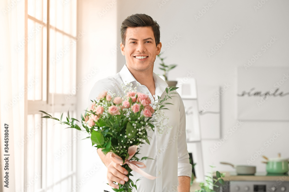 Handsome man with bouquet of flowers indoors