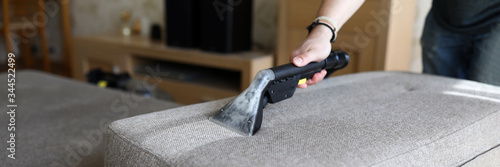 Photographie Male housekeeper hand cleaning sofa with washing suction cleaner