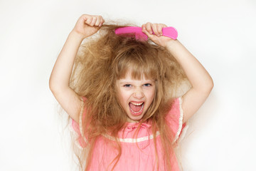 Wall Mural - a little girl with unruly, tangled long hair in a pink dress on a white background tries to comb it