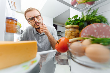 Wall Mural - Man Looking Inside Fridge Full Of Food.