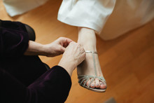 Midsection Of Bridesmaid Assisting Bride Wearing High Heels During Wedding Ceremony