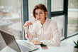 © Катя Іваськевич - young businesswoman working on laptop in the office. portrait of businesswoman. working in the office. happy business woman talking on the phone in the workplace. focused woman working.