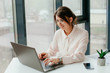 © Катя Іваськевич - young businesswoman working on laptop in the office. portrait of businesswoman. working in the office. happy business woman talking on the phone in the workplace. focused woman working.