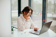 © Катя Іваськевич - young businesswoman working on laptop in the office. portrait of businesswoman. working in the office. happy business woman talking on the phone in the workplace. focused woman working.