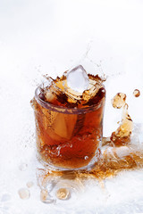 whiskey cocktail with cola and ice in a transparent glass with beautiful splashes