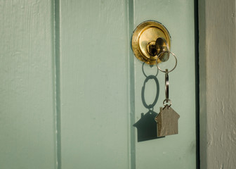 A house front door key with a house shaped key ring