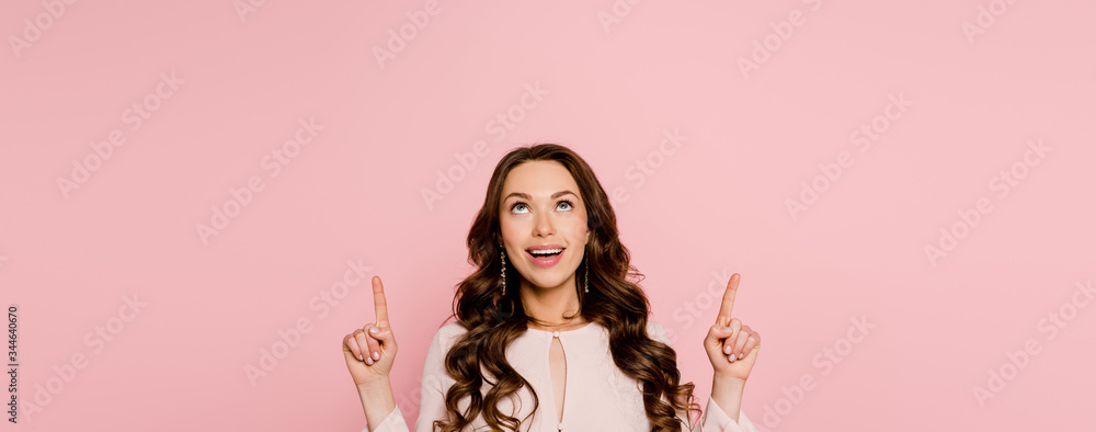 panoramic shot of cheerful girl pointing with fingers and looking up isolated on pink - obrazy, fototapety, plakaty 